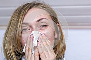 Portrait of ill sick woman sneezing, coughing, blowing her nose in handkerchief on light background, close-up. Concept diseases of