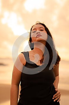 portrait image of an Asian woman with black hair and an angry expression standing on the beach in her black clothes