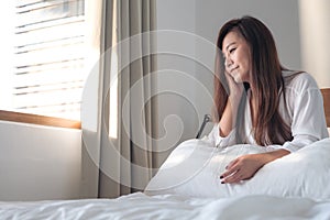 Portrait image of a beautiful Asian woman sitting on the bed after woke up with feeling happy