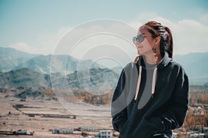 Portrait image of a beautiful Asian woman standing on the top of view point with Leh city
