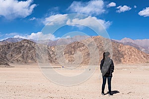 A beautiful Asian woman tourist standing and turn back in front of mountain and blue sky background