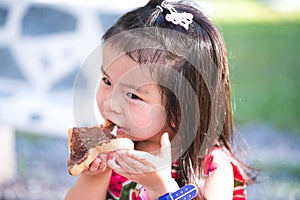 Portrait image child 3-4 years old. Adorable kid enjoying delicious chocolate-covered bread. Hungry children eating snacks at park