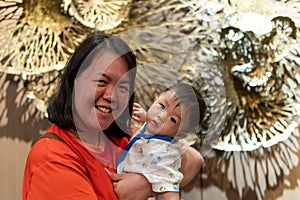 Portrait image of Cute and adorable Asian Chinese baby boy carry up by mother