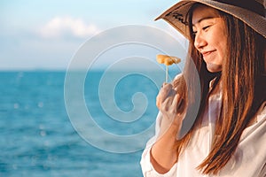 Portrait image of a happy beautiful asian woman enjoy eating pineapple by the sea with clear blue sky