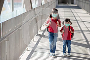 Portrait image of little cute Asian children siblings wearing a face mask and take a school bag. Back to school and kids.