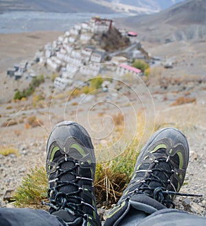 Portrait image of traveler with trekking shoes resting near the Key Monastery