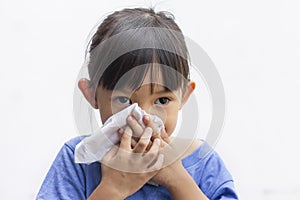 A little girl blowing her runny nose by tissue paper.