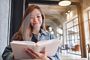 A young beautiful asian woman sitting and reading book