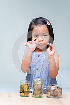 Portrait imaged. Asian child girl holding silver coins in her hands. Save money for the future. Coins cash in grass jar.