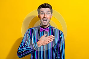 Portrait of impressed astonsihed guy dressed stylish shirt bow tie hold arm on chest staring isolated on vibrant yellow