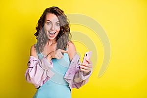 Portrait of impressed funny person open mouth smile indicate finger phone isolated on yellow color background