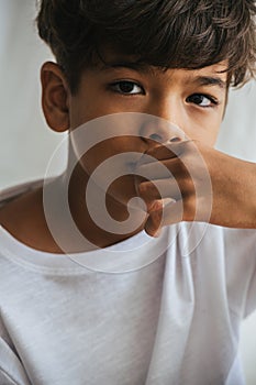 Portrait of an indian asian kid touching his mouth with hand. Close up