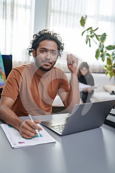 Portrait of a indian designer doing his work with laptop in office