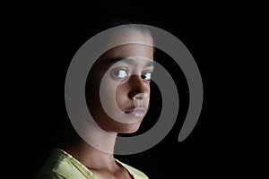 Portrait of an Indian little girl with short hair. Beautiful eye of a child on black background.