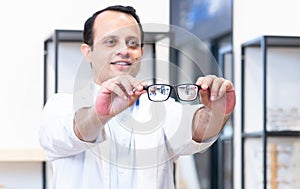 Portrait of Indian middle aged ophthalmologist or optometrist man work at optometry clinic, holding and showing new collection of