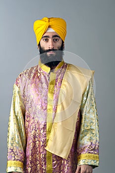 Portrait of Indian sikh man with bushy beard standing against a grey background