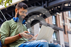 Portrait Indian student programmer using laptop computer in park