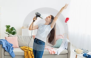 Portrait of Indian teenage girl dancing and singing karaoke, using blowdryer as microphone, having domestic concert