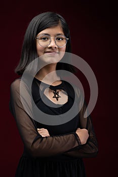 a portrait of an indian young woman wearing glasses, in front of a red background