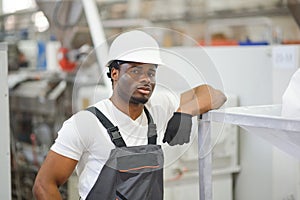 Portrait of industrial engineer. Smiling factory worker with hard hat standing in factory production line