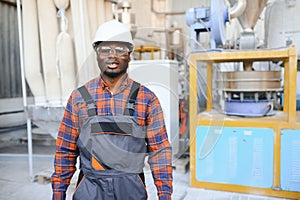 Portrait of industrial engineer. Smiling factory worker with hard hat standing in factory production line