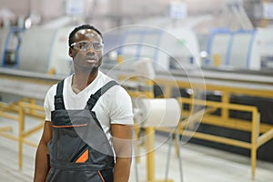 Portrait of industrial engineer. Smiling factory worker with hard hat standing in factory production line
