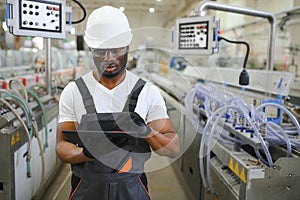 Portrait of industrial engineer. Smiling factory worker with hard hat standing in factory production line