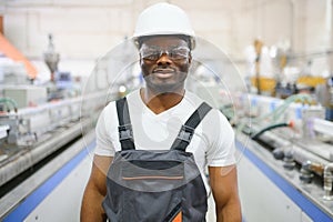 Portrait of industrial engineer. Smiling factory worker with hard hat standing in factory production line