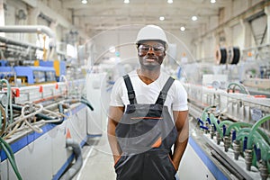 Portrait of industrial engineer. Smiling factory worker with hard hat standing in factory production line