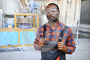 Portrait of industrial engineer. Smiling factory worker with hard hat standing in factory production line