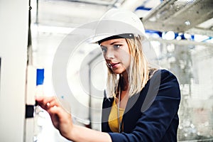 A portrait of an industrial woman engineer in a factory checking something.