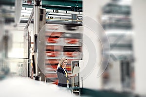 A portrait of an industrial woman engineer holding laptop in a factory.