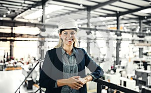 A portrait of an industrial woman engineer standing in a factory.