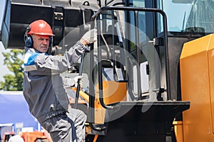 Portrait industrial worker driver in helmet and headphones against background of excavator. People mining concept