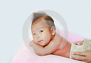 Portrait of infant baby on white background lying on pink pillow