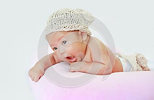 Portrait of infant baby on white background lying on pink pillow