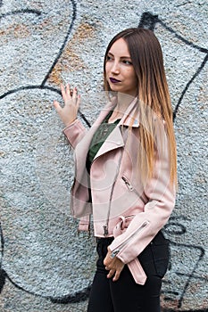 Portrait of informal fashionable girl on graffiti wall background