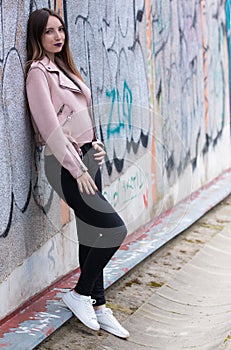 Portrait of informal fashionable girl on graffiti wall background