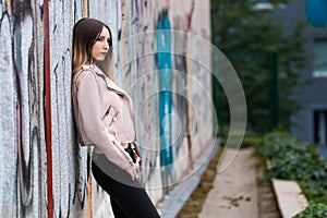 Portrait of informal fashionable girl on graffiti wall background