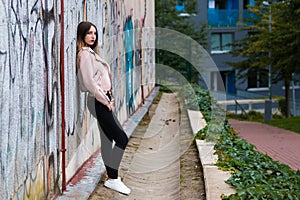 Portrait of informal fashionable girl on graffiti wall background