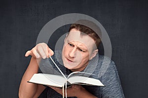 Portrait of inquisitive man reading big book and flipping page
