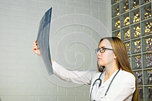 Portrait of intellectual woman healthcare personnel with white labcoat, looking at full body x-ray radiographic image