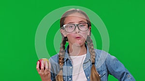 Portrait of intelligent girl eating healthful vitamin apple smiling looking at camera on green screen. Positive