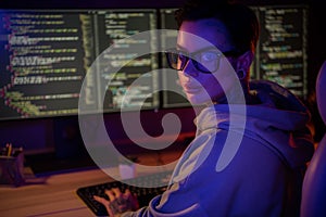 Portrait of intelligent hipster hacker girl sitting chair keyboard typing operating script dark room indoors