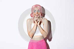 Portrait of intrigued beautiful girl with pink wig and bright makeup, looking left at something tempting, standing in