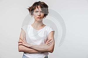 Portrait of irritated woman with short brown hair in basic t-shirt frowning and looking at camera