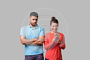 Portrait of jealous boyfriend looking suspicious at woman. isolated on gray background, indoor studio shot