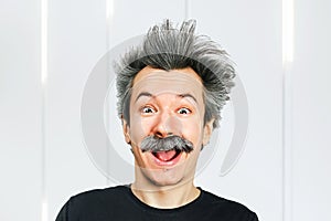 Portrait of jocular aging man with grey long hair smiling with open mouth, in Einstein manner