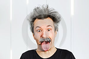 Portrait of jocular aging man with grey long hair sticking his tongue out in Einstein manner