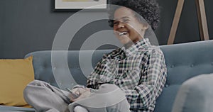 Portrait of joyful African American boy watching TV and laughing enjoying cartoon at home
